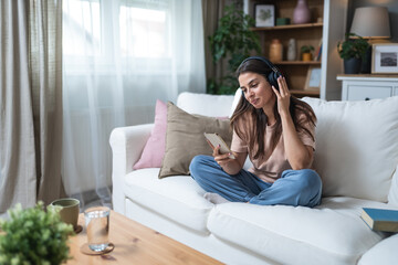 Simple living. Young beautiful relaxed woman sitting alone at home on sofa, listening podcast or...