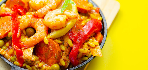 A black pan filled with a variety of food including shrimp, peppers, and corn
