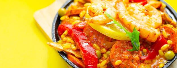 A black pan filled with a variety of food including shrimp, peppers, and corn