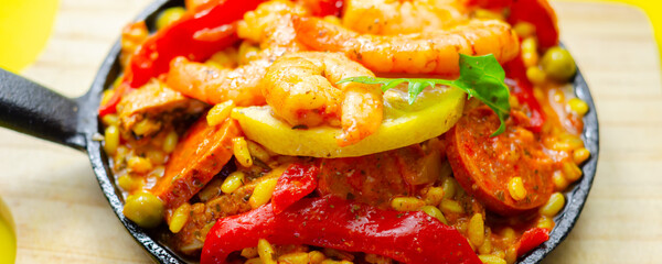 A black pan filled with a variety of food including shrimp, peppers, and corn