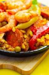 A black pan filled with a variety of food including shrimp, peppers, and corn