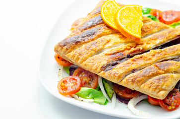 A plate of food with a pastry and a slice of orange on top