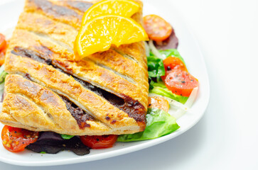 A plate of food with a pastry and a slice of orange on top