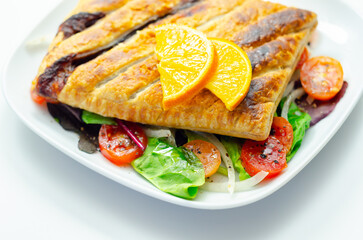 A plate of food with a pastry and a slice of orange on top