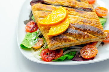A plate of food with a pastry and a slice of orange on top