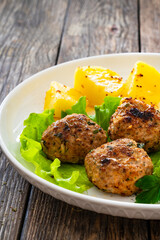 Baked meatballs, boiled potatoes, beetroots, fresh vegetables and mayonnaise served on white plate on wooden table
