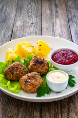 Baked meatballs, boiled potatoes, beetroots, fresh vegetables and mayonnaise served on white plate on wooden table
