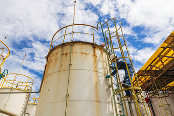 Male worker climbs up the ladder inspection stainless tank work at height