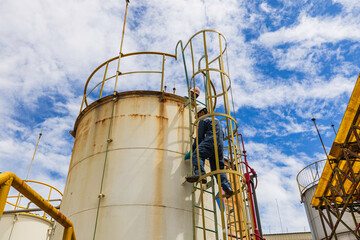 Male worker climbs up the ladder inspection stainless tank work at height