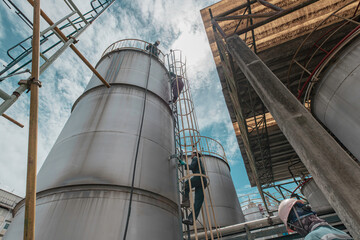 Male worker climbs up the ladder inspection stainless tank work at height