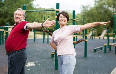 Man and a woman doing gymnastics on an outdoor sports ground