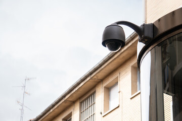 Security surveillance cameras in front of high-rise condominium. CCTV camera home security system. A camera is mounted on a pole in front of a building is black and has a round lens. recognition, AI, 
