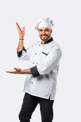 Smiling Indian Asian chef or professional cook pointing, isolated white background