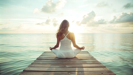 Fototapeta premium Tranquil scene of a woman meditating on a wooden pier at sunrise, facing the serene ocean, promoting relaxation and mindfulness.