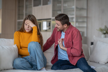 Squabble of married couple on sofa in living room. Abusive man making excuses aggressively attacks...