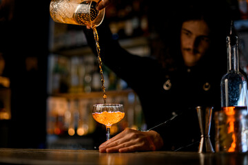 Specialist bartender mixing a cocktail with alcoholic drinks in glass