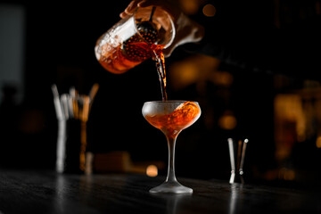 Glass with whiskey, rum, cognac or another strong alcoholic drinks and hands making a cocktail
