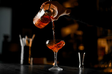 Cocktail glass with strong drinks on a dark wood bar counter