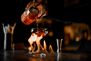 Master make a alcohol strong drinks with fire on a dark background