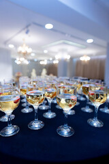 A table full of wine glasses with a blue background. Scene is celebratory and festive