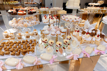 A table full of desserts with a pink bow on it. The desserts are arranged in a way that makes them look like they are on display at a bakery. Scene is celebratory and inviting