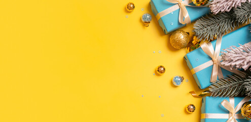 Yellow-blue Christmas banner background with gifts and festive decorations top view. Copy space