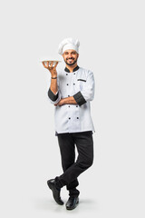 Indian asian young Chef in uniform happily presenting empty white ceramic plate on white background