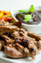 A plate of meat and vegetables with a sauce on the side