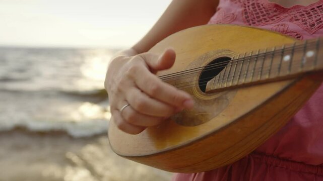 Female fingers hitting the strings of a mandolin or ukulele