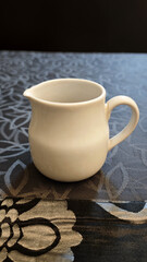 Freshly Poured Sugar Syrup in a Simple White Porcelain Pitcher on a Patterned Tablecloth