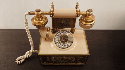 Vintage Gold and Cream Rotary Telephone with Ornate Detailing on Wooden Surface