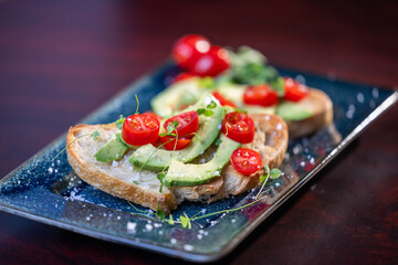 A slice of toasted sour dough bread with avocado and tomato on top
