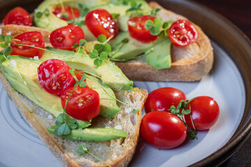 A slice of toasted sour dough bread with avocado and tomato on top
