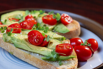 A slice of toasted sour dough bread with avocado and tomato on top