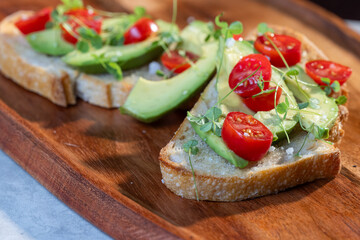 A slice of toasted sour dough bread with avocado and tomato on top