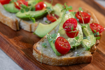A slice of toasted sour dough bread with avocado and tomato on top