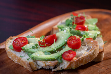A slice of toasted sour dough bread with avocado and tomato on top