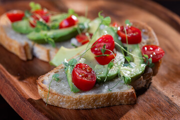 A slice of toasted sour dough bread with avocado and tomato on top