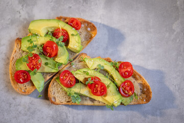 A slice of toasted sour dough bread with avocado and tomato on top