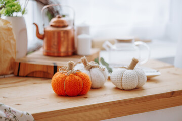Bright kitchen with wooden kitchen utensils and three decorative pumpkins. Stylish decor concept for home, Halloween or autumn harvest.