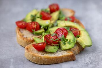 A slice of toasted sour dough bread with avocado and tomato on top