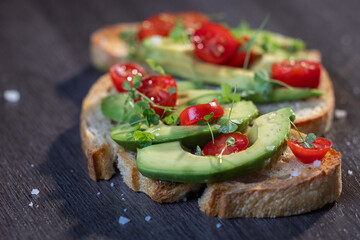 A slice of toasted sour dough bread with avocado and tomato on top
