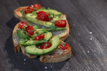 A slice of toasted sour dough bread with avocado and tomato on top