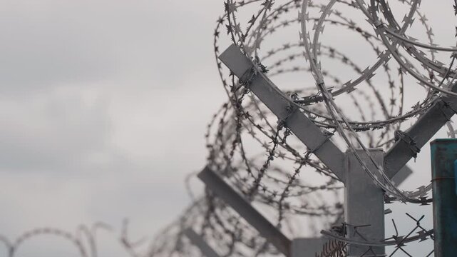 Barded wire close-up shot, airport perimeter fence. cloudy day. Boundary barrier isolation, border line and barbwire