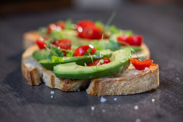 A slice of toasted sour dough bread with avocado and tomato on top