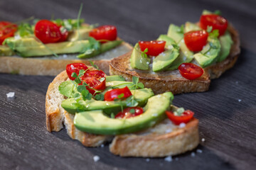A slice of toasted sour dough bread with avocado and tomato on top
