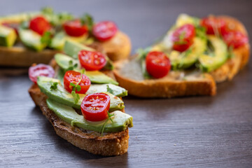A slice of toasted sour dough bread with avocado and tomato on top