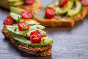 A slice of toasted sour dough bread with avocado and tomato on top