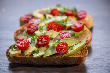 A slice of toasted sour dough bread with avocado and tomato on top