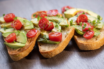 A slice of toasted sour dough bread with avocado and tomato on top